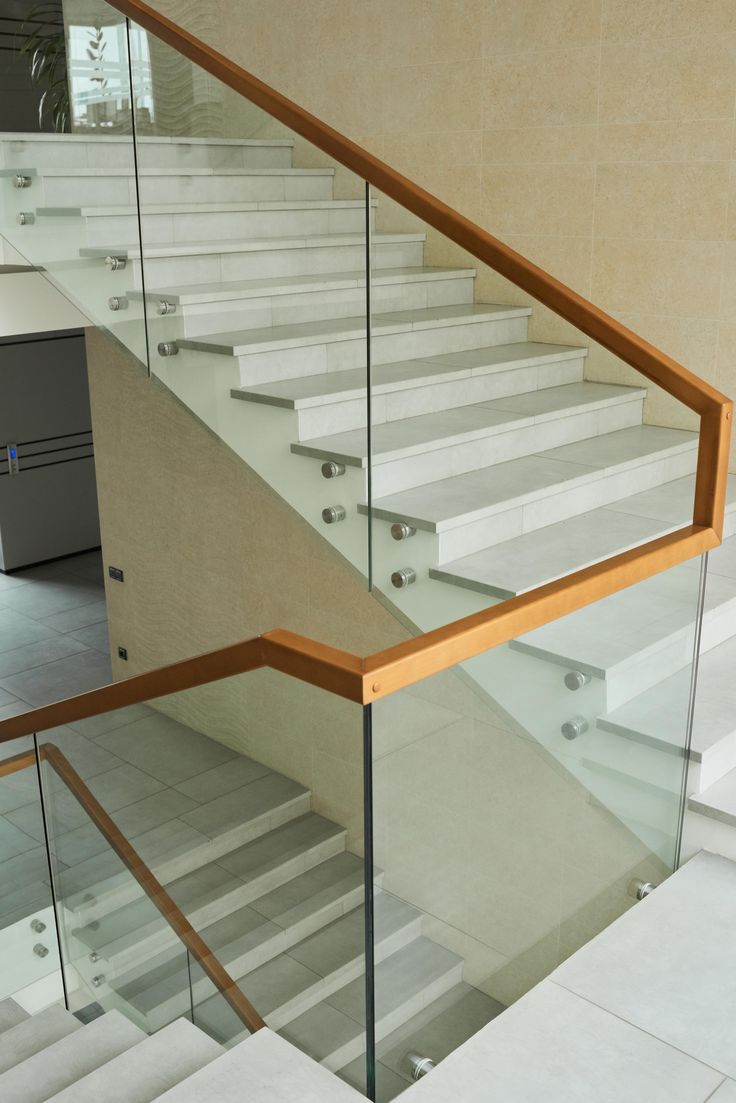 Clear glass staircase railing with wooden handrail